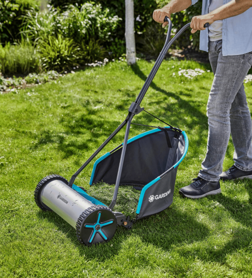 En person klipper gräset med en Cylindergräsklippare med uppsamlare.